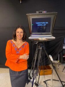 Apresentadora Angela Santangelo lendo teleprompter com fluência e naturalidade durante gravação profissional de vídeo